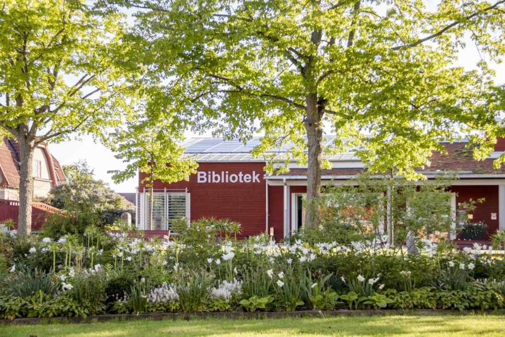 Mönsterås bibliotek i vårgrönskande park.