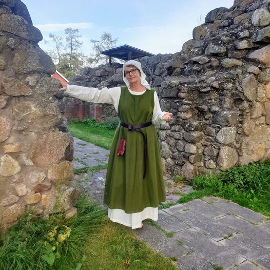 Kvinna i medeltida dräkt guidar i Kronobäcks klosterkyrkoruin.
