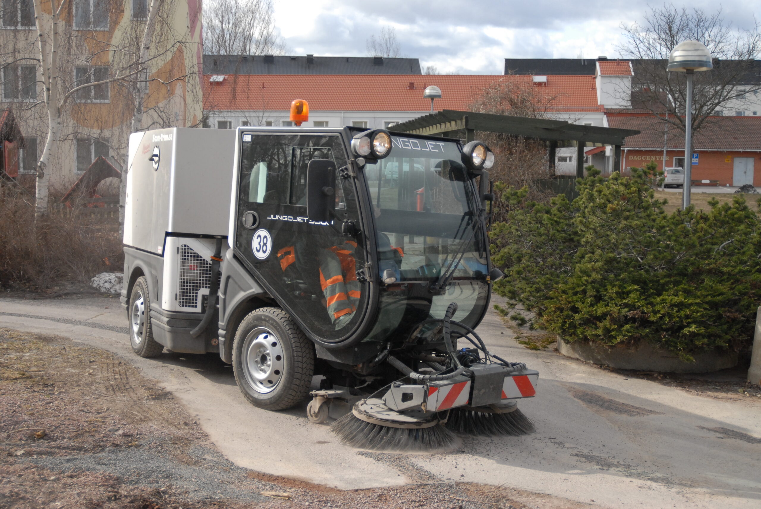 Truck för sandupptagning tar upp sand på gång- och cykelväg. Foto.