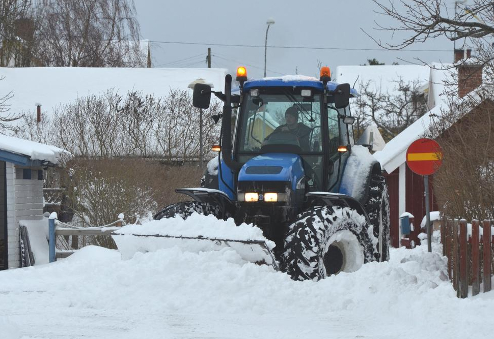 Traktor plogar en gata i ett bostadsområde. Foto.